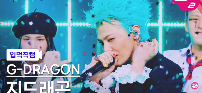 Title card for a G-Dragon stage performance On m. Countdown he's holding a microphone close to his face and you can see his brightly colored manicure