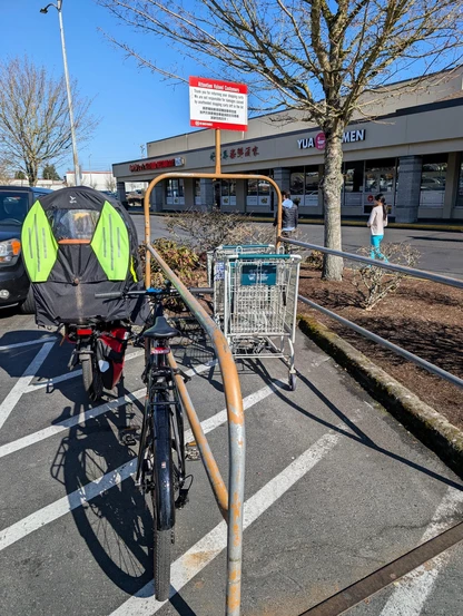 My bike and wife's e-bike locked onto the guard rail of one of the "return the cart here" spots.