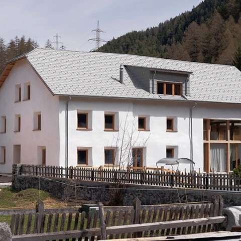 Finished rough lime plaster on the straw bale retrofitted house with metal roof and angled window openings looking gorgeous.