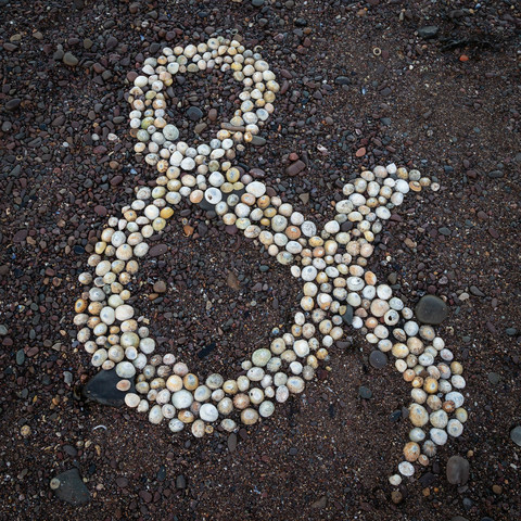 An ampersand on a beach, created by arranging some unoccupied limpet shells.