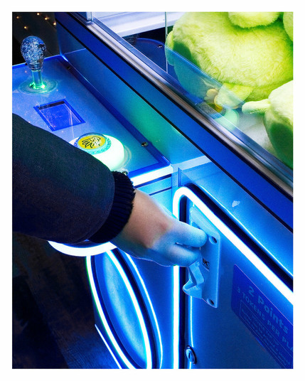 Close up of a hand putting tokens into a claw machine.