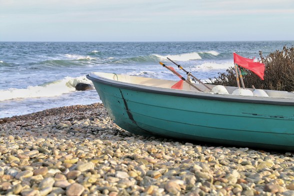 Türkisfarbenes Ruderboot an Ostsee-Steinstrand