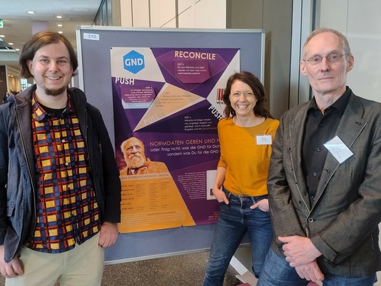 Julian Jarosch, Denise Jurst-Görlach und Thomas Kollatz stehen vor dem Poster des Projekts Buber-Korrespondenzen Digital"