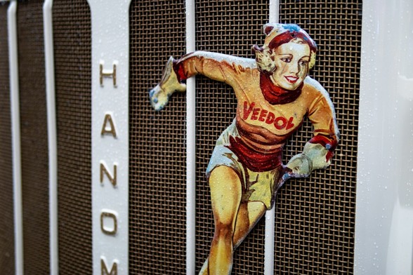 Ein Nahaufnahme Foto eines Hanomag Oldtimers. Es ist eine Frau auf der Motorhaube abgebildet auf deren Oberteil Veedol steht.
