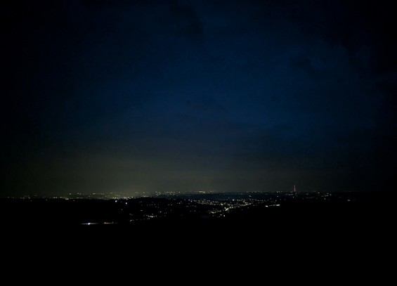 Dark foreground leads to lights of a distant city.  Dark sky above reflects the light from below.
