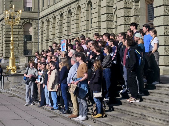 Eine Gruppe von Menschen auf der Treppe vor dem Eingang zum Hauptgebäude der ETH-Zürich mit einem Schild mit der Aufschrift "Stand up for Science"