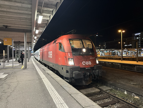 Vorne hängt eine rote ÖBB-Taurus am Zug