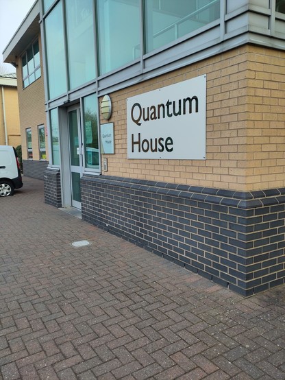 Skilt med teksten "Quantum House" på en gul murbygning