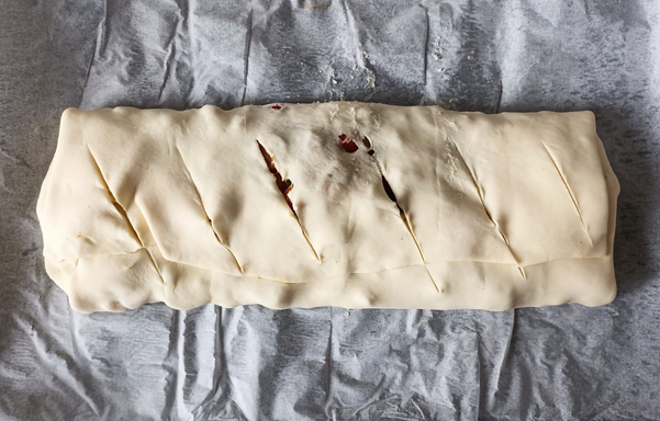 Der fertig gerollte und 6 mal eingeschnittene Strudel vor dem Backen auf dem Blech.
