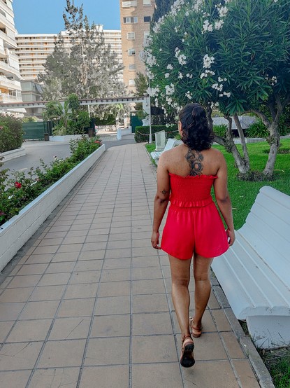 Una chica preciosa con un vestido rojo caminando vista de espaldas