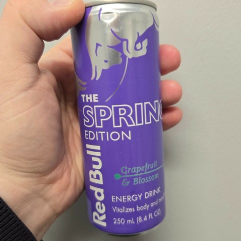 Photograph of a white person's hand holding a purple Red Bull can labeled "The Spring Edition." It says it's Grapefruit and Blossom flavored.