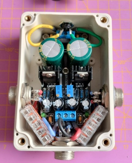 a view into the enclosure. the main board is tugged into place. on the upper edge is the input barrel jack. bottom left and right are three GX16 connectors for the outputs. the cables are joined using WAGO connectors that are squeezed diagonally left and right for plus and minus output, and underneath the board for GND.