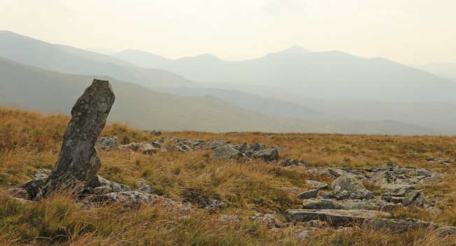 a single upright finger of rock in the middle of nowhere on a remote Welsh mountain, beyond, even more mountains fade into the hazy distance.