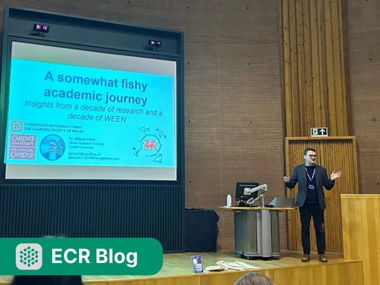 William Perry standing at a podium in front of his first presentation slide, titled "A somewhat fishy academic journey: insights from a decade of research and a decade of WEEN".