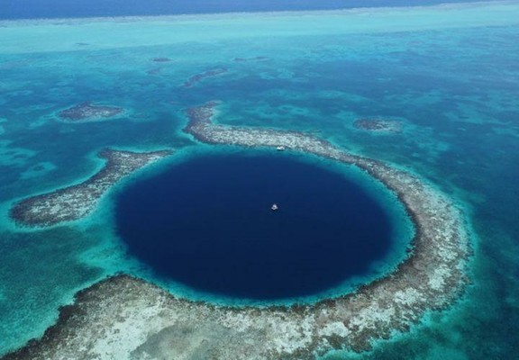 Drohnenaufnahme aus 200 Metern Höhe mit Blick nach Osten, die das „Great Blue Hole“ mit der in der Mitte verankerten Bohrplattform zeigt. Im Hintergrund ist der windzugewandte Rand des Lighthouse Reef Atolls zu sehen.

Foto: E. Gischler
