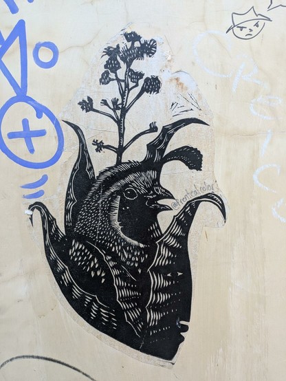 Imagen en blanco y negro de ave saliendo de maguey florecido. Es un papel pegado en una pared.