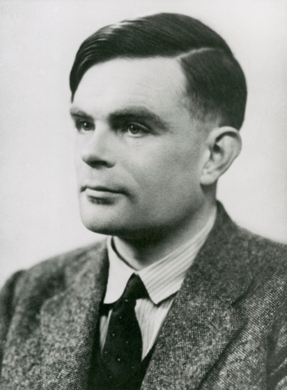 The image is a black and white portrait of a young man. He is wearing a textured, tweed-like suit jacket over a white shirt with a dark tie. The man has a slicked-back hairstyle with a distinct parting on the side, which was a popular style in the early to mid-20th century. His expression is serious and contemplative, with his gaze directed slightly to the side. The background is plain and light-colored, providing a neutral backdrop that focuses attention on the subject. The overall composition and attire suggest a formal or professional setting.

It's a picture of Alan Turing