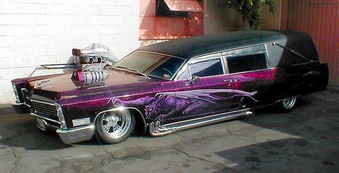 A vintage Cadillac hearse painted metallic purple with a stylized graphic of the Grim Reaper on the side. The car has been lowered, and a supercharged engine has been installed. The intake and the blower extend up out of the hood. The roofline has been channelled and lowered, so the slope on the windshield is much steeper than normal. The car has a black vinyl top and mag wheels.