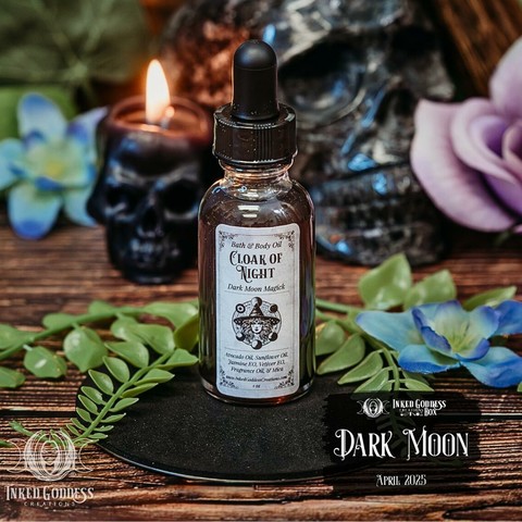 A clear glass vial sits on a black disc. The vial is filled with a clear-ish liquid and has an eyedropper in the screw-on cap. The label reads, "Bath & Body Oil / Cloak of Night / Dark Moon Magick / avocado oil, sunflower oil, jasmine essential oil, vetiver essential oil, fragrance oil, & mica. This is one of the items in the exclusive April 2025 "Dark Moon" Inked Goddess Creations Box.