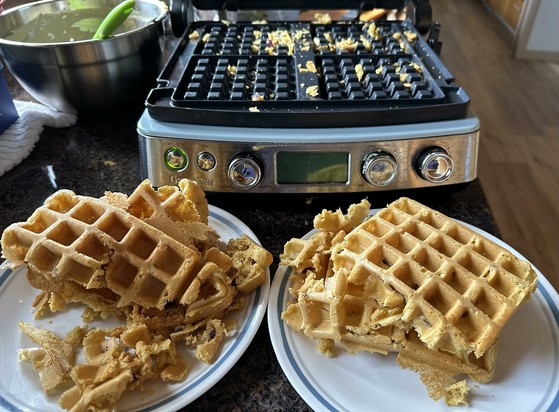 Partly torn apart chickpea waffles in front of of a waffle maker