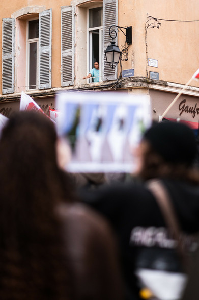 Une personne regarde passer la manif par sa fenêtre
