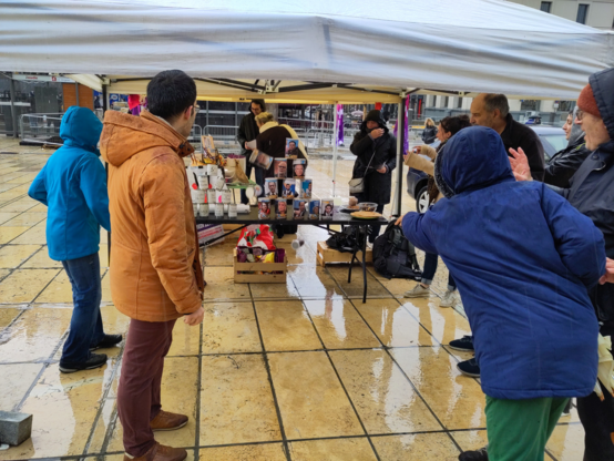 Une passante lance un balle sur le chamboule-tout avec les têtes de nos dirigeant•es