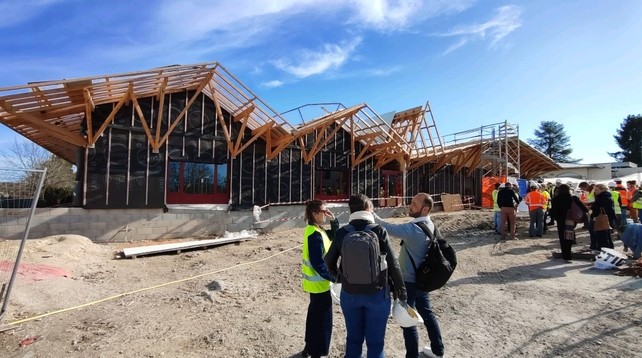Straw timber house in the making with folks visiting