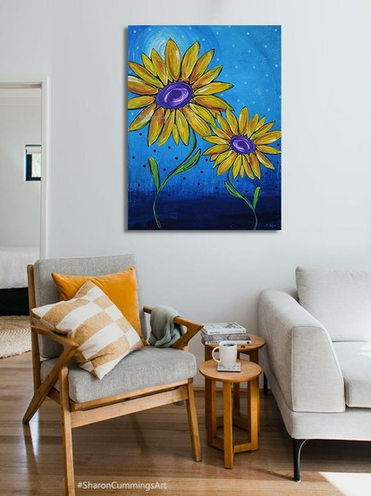 Colorful yellow sunflowers on a blue background by artist Sharon Cummings.  Set in a furniture setting.