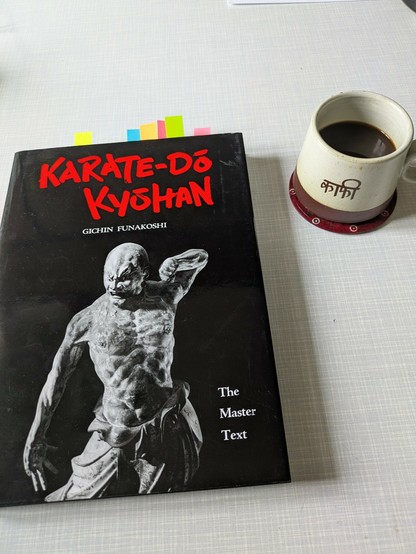 Photograph of a cup of coffee and the karate book by Gichin Funakoshi