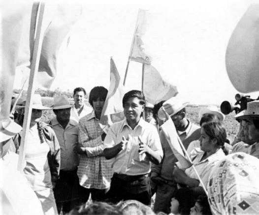 Historical black and white photo of Cesar Chavez with farm workers