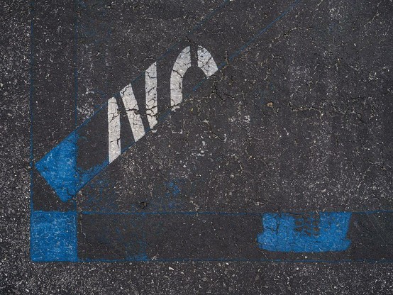 Old markings of handicap parking space with about half of "No" remaining.