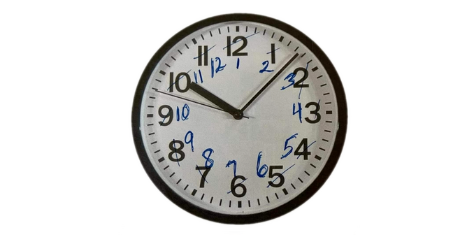 a simple wall clock, but instead of adjusting the clock by one hour, the number 1 has been scribbled out and a 2 written beside it, the number 2 has been scribbled out and a 3 added, etc
