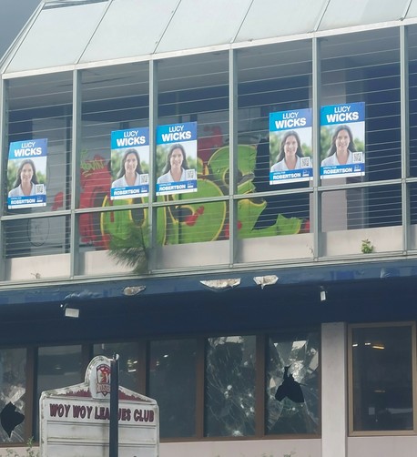 Outside of Woy Woy Leagues Club, with broken windows and graffiti. a row of election posters are visible on the second story. How did they get there?