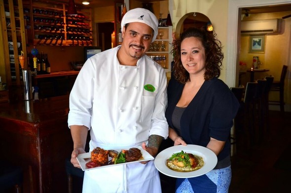 Chef Marcos DeSouza with his Citrus Glazed Long Island duck dish as manager Erica White holds the Roasted Chicken dish, at Bia Bistro in Cohasset. Photo by Debee Tlumacki for the Boston Globe