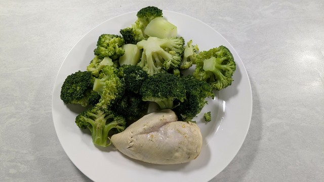 A plate featuring steamed broccoli and a portion of cooked chicken breast.