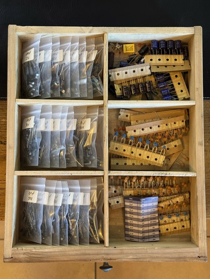 Wooden drawer filled with capacitors sorted by value in little plastic bags