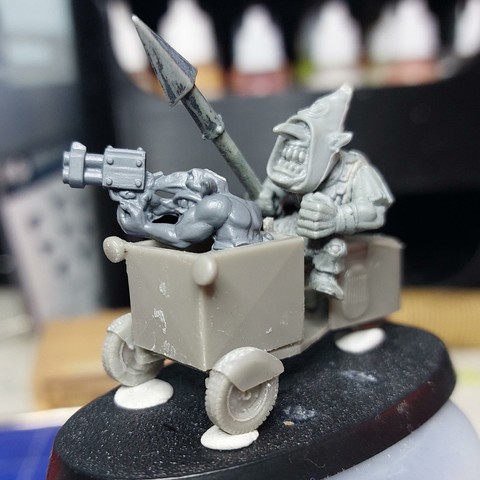 Small 1940s motorised tricycle with a transport box on the front. There's a grot with a gun sticking out the box and a goblin with spear sat in the driver's position