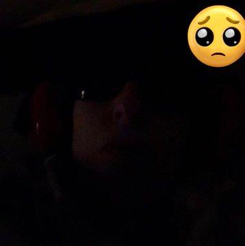 Woman bed in a very dark room with ear defenders and light block glasses.