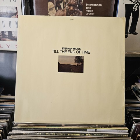 Album cover features small rectangular photograph of SM seated beneath a tree beside a small stream.
