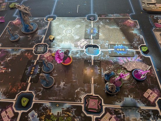 Close-up of game board. Several minis, cards, tokens and board pieces on a game mat.