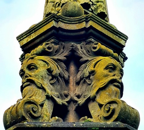 The heads of two foliate green men on a Victorian sundial in Glasgow.