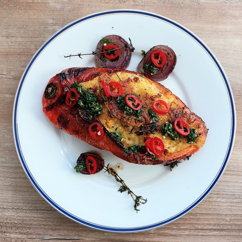 Das fertige Gericht auf dem Teller. Die Paprika hat sich etwas aufgebläht, man sieht die gelbe Füllung. Mit eineigen Zwiegelscheiben, Thymian, Chiliringen + dem Petersilienöl garniert.
