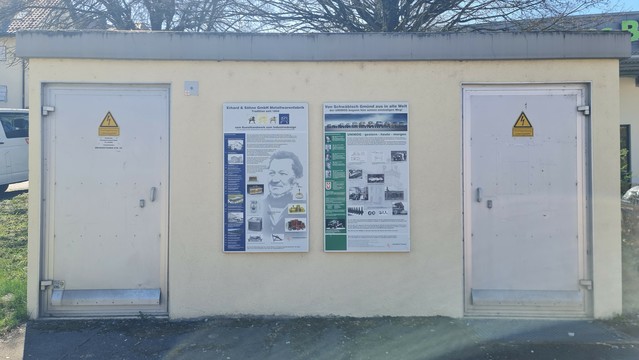 An kleinem Nebengebäude sind an der Wand zwei plakataushänge angebracht, die die Geschichte der Fabrik 'Erhard' erzählen, die auf dem Gelände stand; der 'Unimog' wurde hier produziert.