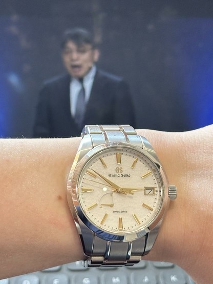 Wrist shot of a Grand Seiko SBGA259 with the GS W&W 2025 keynote in the background
