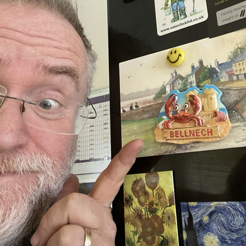 Me pointing at Benllech (spelt wrong) fridge magnet with crab and sandcastle