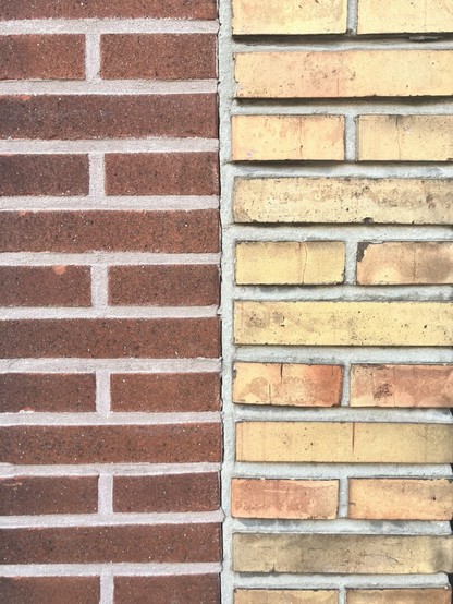 Scheidslijn tussen twee gevels: de linkergevel is van rode bakstenen, de rechtergevel van okergele bakstenen