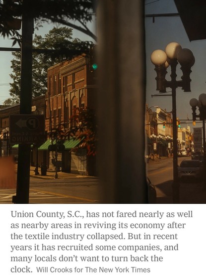 A quiet downtown street in Union County, South Carolina, featuring brick buildings, traffic lights, and lampposts. The scene reflects a historic area, with signs indicating public parking. A soft sunlight casts a warm glow, suggesting a late afternoon ambiance