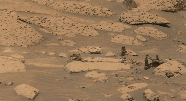 An ochre toned image of Martian rocks and sand captured by the Mars rover Curiosity.