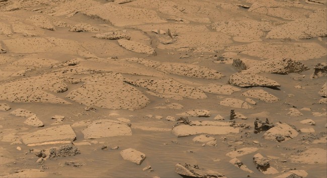 An ochre toned image of Martian rocks and sand captured by the Mars rover Curiosity.