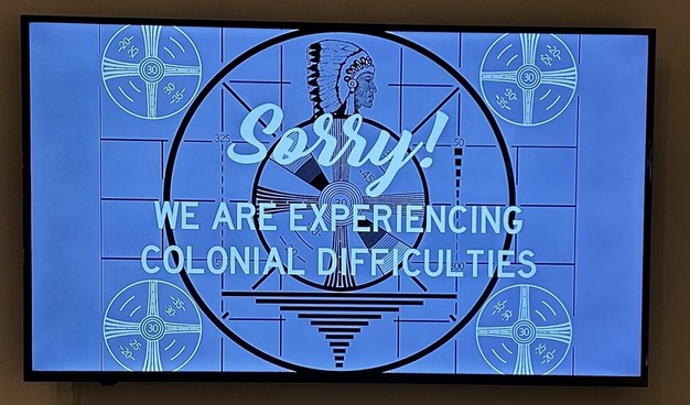 Still from a video that looks like a television error screen:
Sorry! WE ARE EXPERIENCING COLONIAL DIFFICULTIES